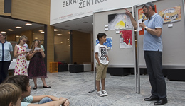 Stadtdekan Helmut Haug interviewt Joussef Utz, der das Bild (im Hintergrund) mit dem mutigen Mose vor dem Pharo gemalt hatim Hintergrund