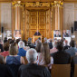 Umgeben von Fotos aller früheren Preisträger begründet Regionalbischof Michael Grabow als Vorsitzender der Jury die Entscheidung für den Preisträger 2017 im Goldenen Saal im Augsburger Rathaus. | Foto: I. Hoffmann   