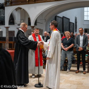 Dekan Frank Kreielmeier und Diakon Ulrich Gottwald gratulieren Diakon Marcus Schirmer zum neuen Dienst.